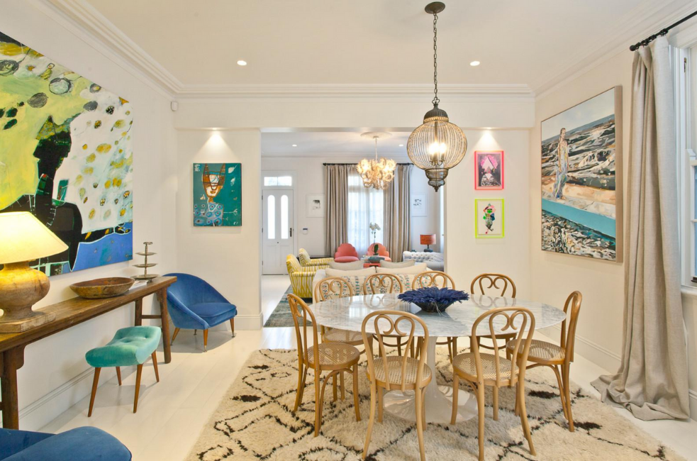 Spacious interconnected living and dining rooms with white painted floors, high ceilings and designer pendant lighting