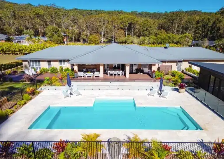 Large modern concrete pool in a spacious backyard with alfresco area and landscaped surroundings