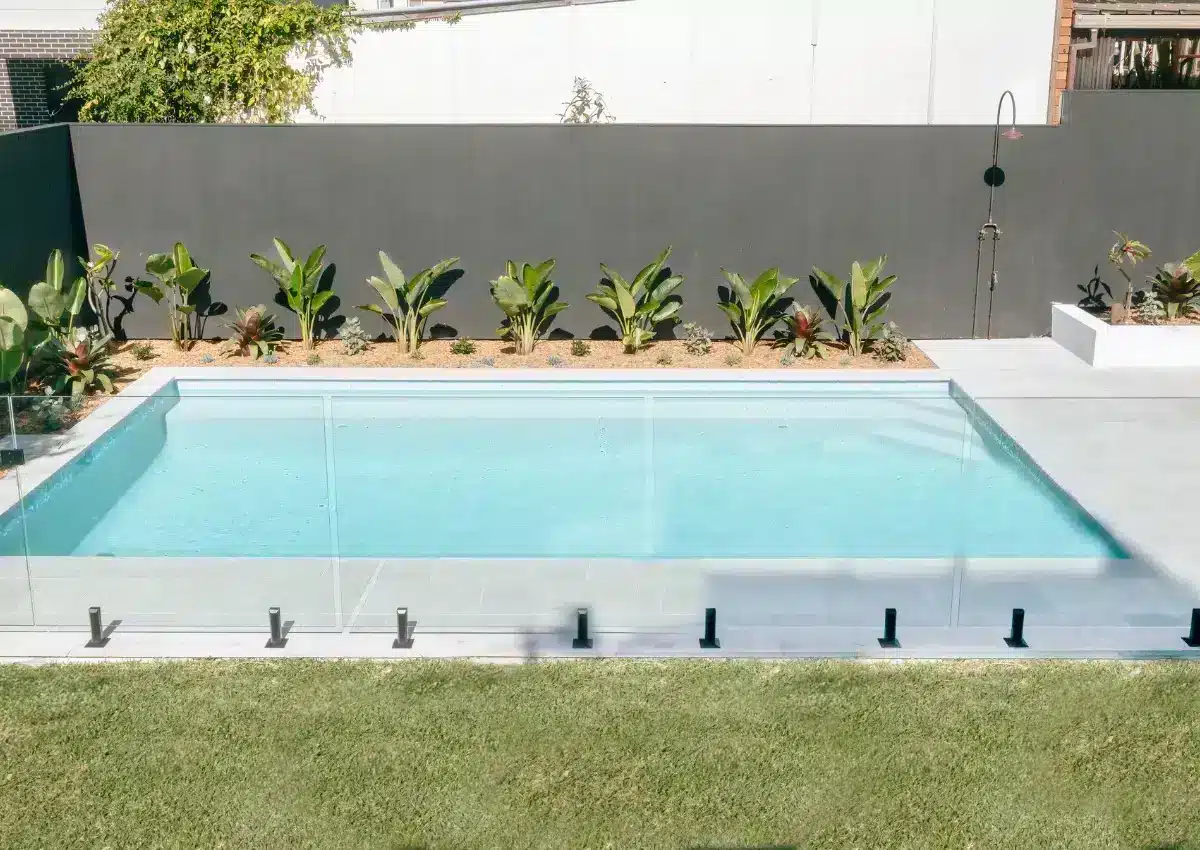 In-ground concrete swimming pool with glass fencing and landscaped backyard in Kirrawee, NSW