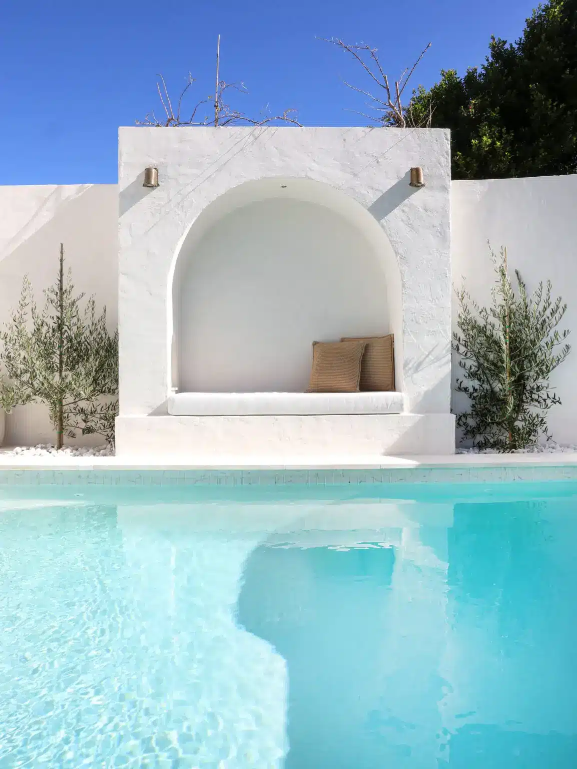 In-ground concrete pool with arched feature wall and minimalist white design in the Archie backyard project, NSW