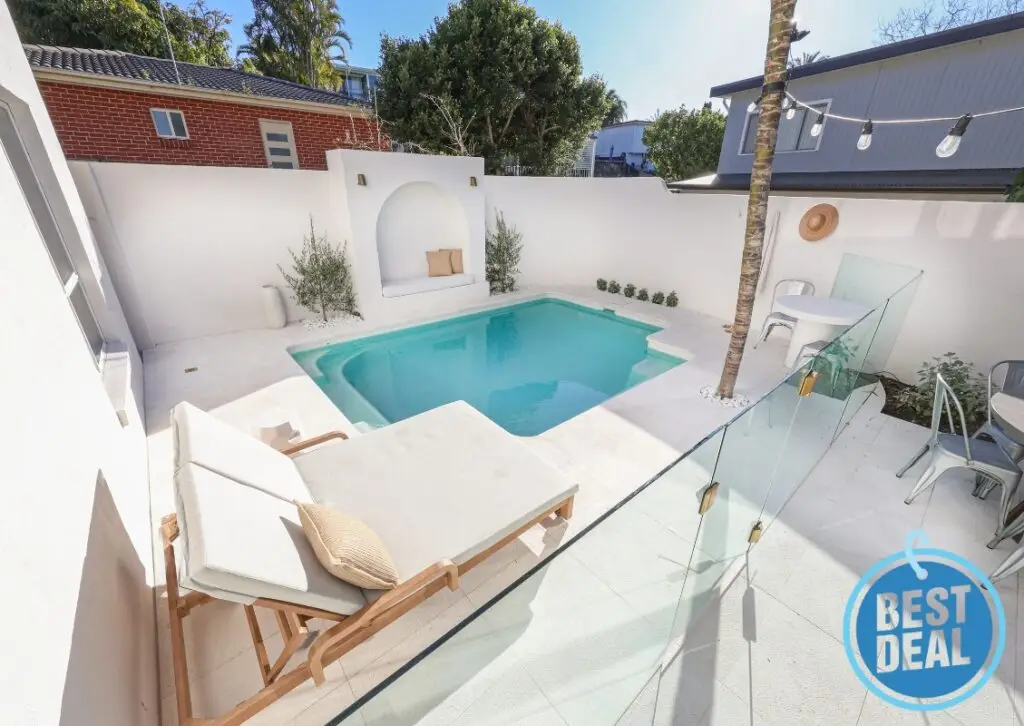 Modern backyard pool installation with white curved walls and minimalist seating area