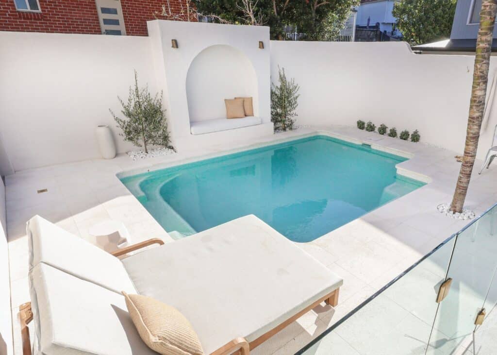 Small backyard plunge pool with curved wall feature and built-in seating by Blue Haven Pools