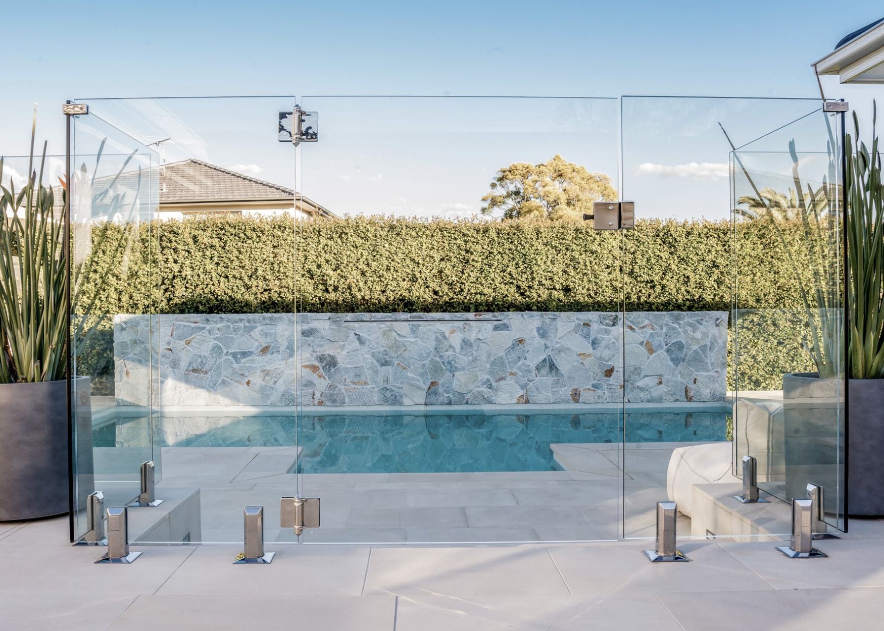 Modern concrete swimming pool in Sydney with stone feature wall and outdoor design