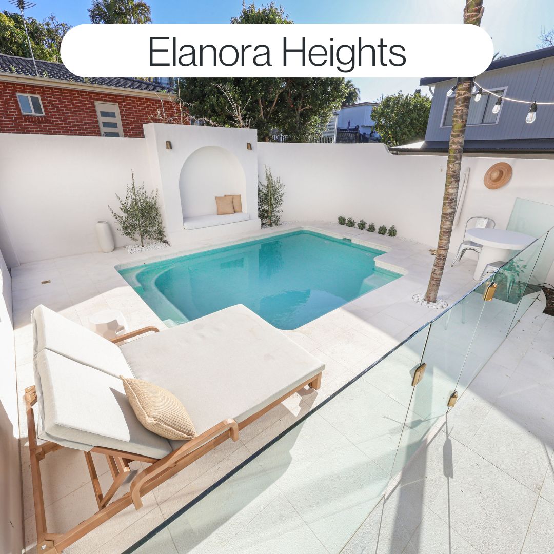 Compact backyard swimming pool in Elanora Heights with white paving, curved pool design, glass fencing and relaxed coastal outdoor living