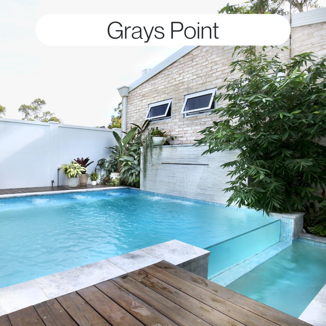 Backyard swimming pool in Grays Point with raised spa, tiled water feature wall, timber deck and tropical landscaping