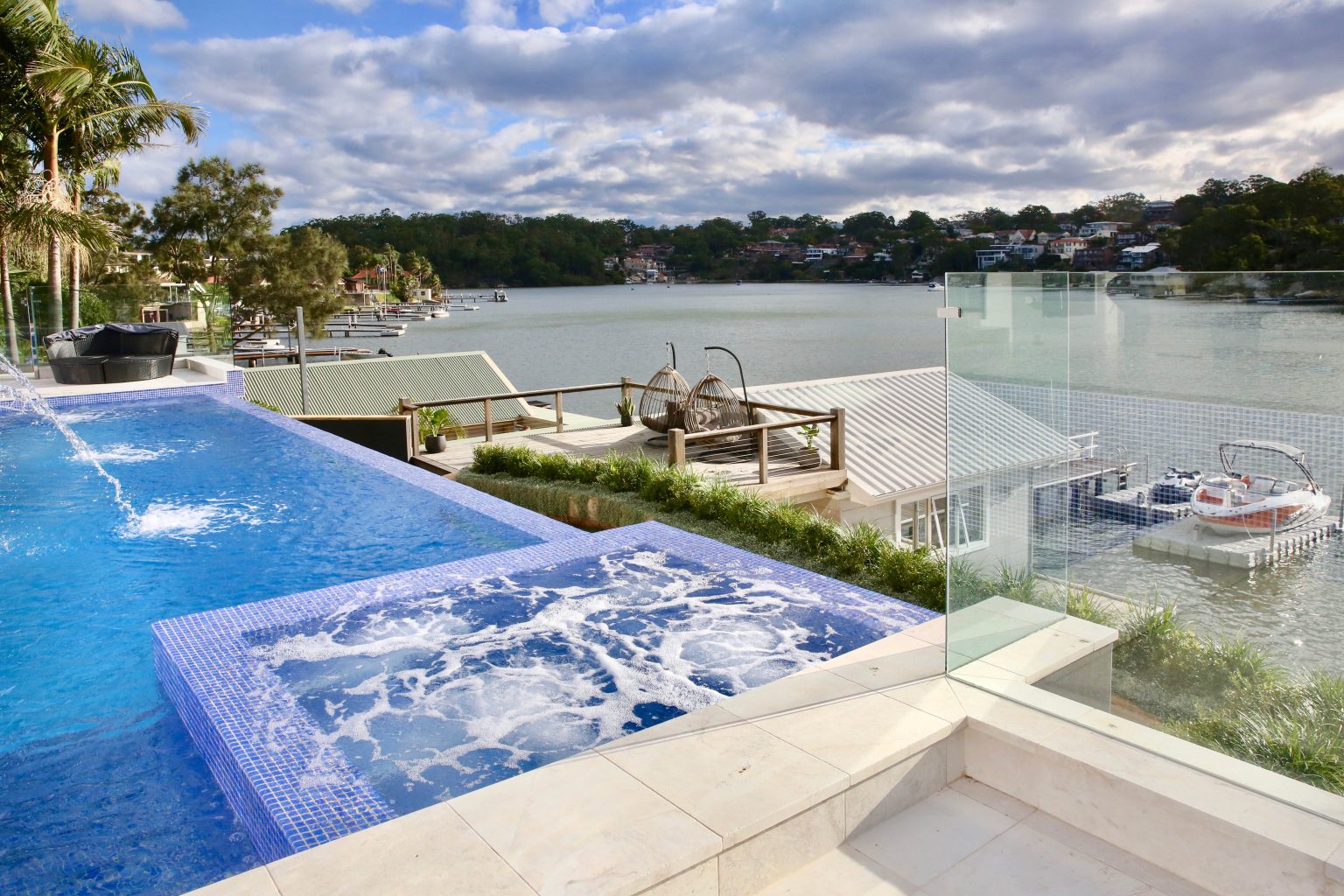Disappearing wet edge tank on a fully tiled custom concrete pool built for a sloping waterfront block