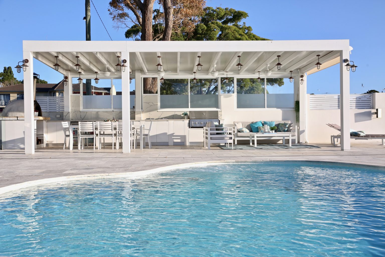 Resort-style backyard pool area with outdoor furniture, lighting and styled entertaining space