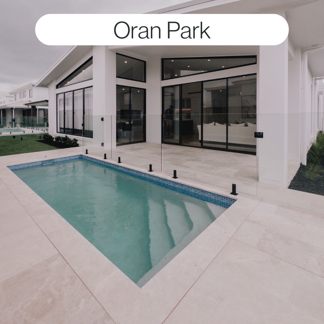 Modern swimming pool in Oran Park beside a contemporary home with glass fencing, light paving and clean architectural outdoor design