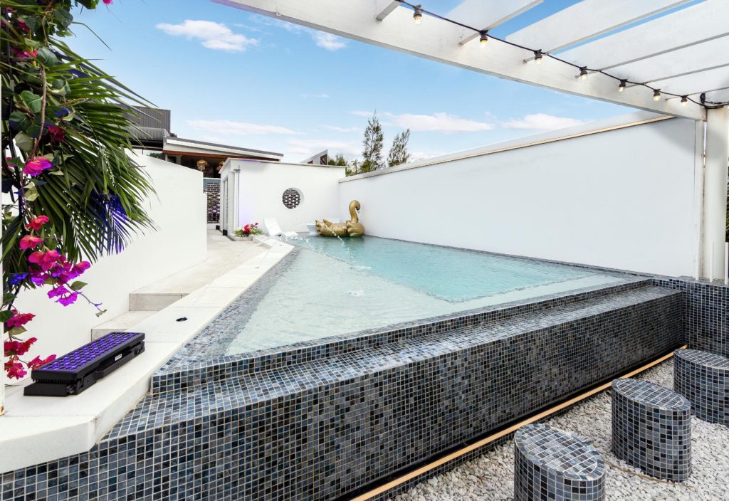 Modern infinity edge pool with raised tiled wall, clean lines and private outdoor entertaining area