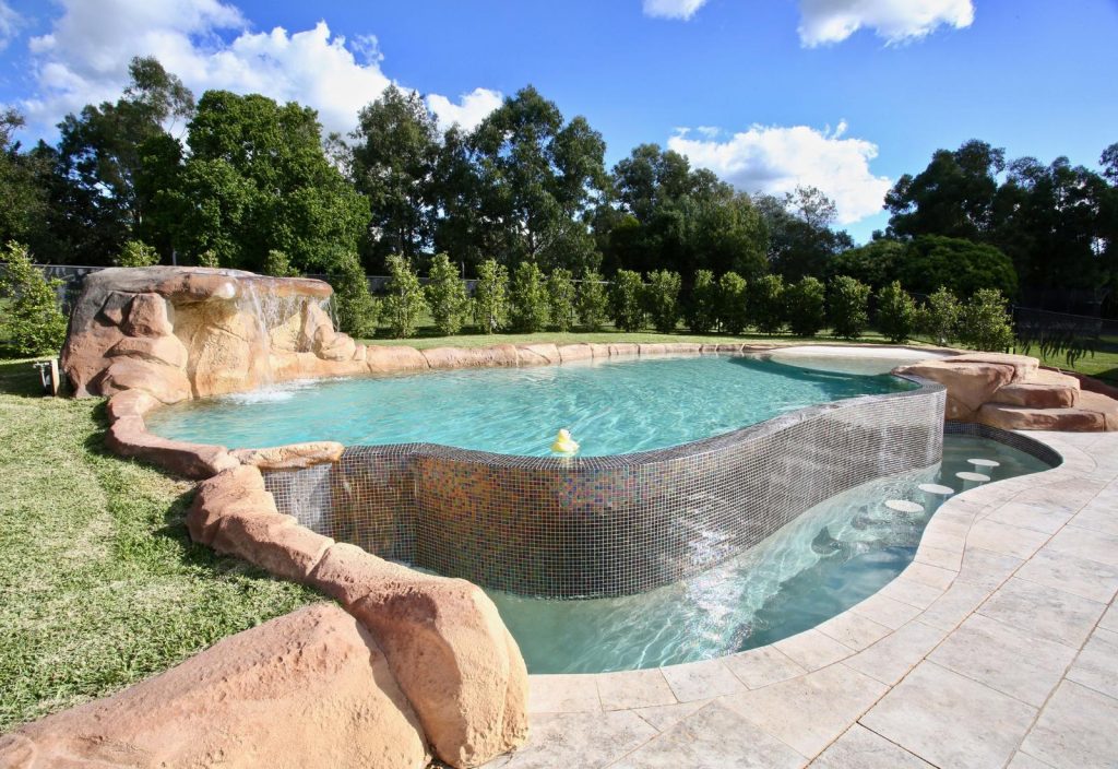Luxury infinity edge pool with rock feature, curved edge and landscaped backyard in NSW