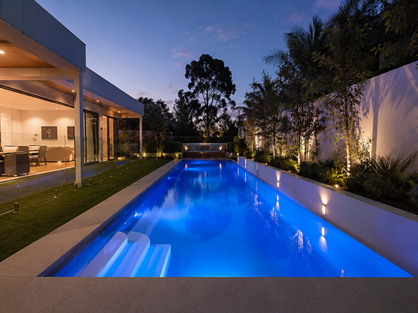 Narrow Sydney backyard pool illuminated with blue LED pool lights