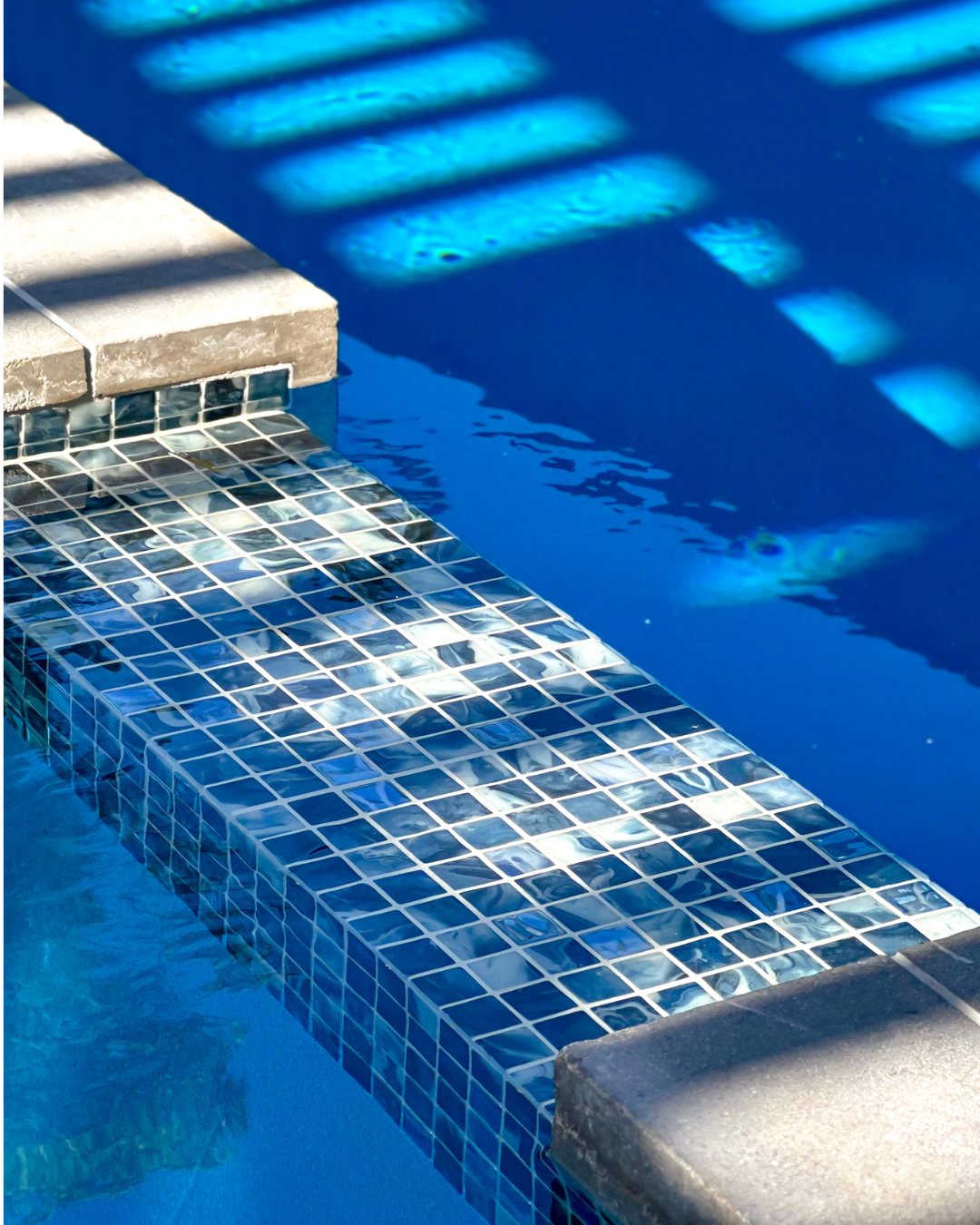 Tiled pool spa spillway integrated into a modern swimming pool design