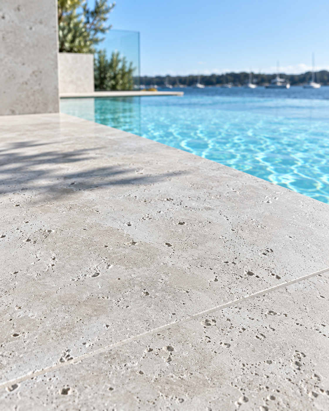 Travertine tumbled pool tile material beside a swimming pool
